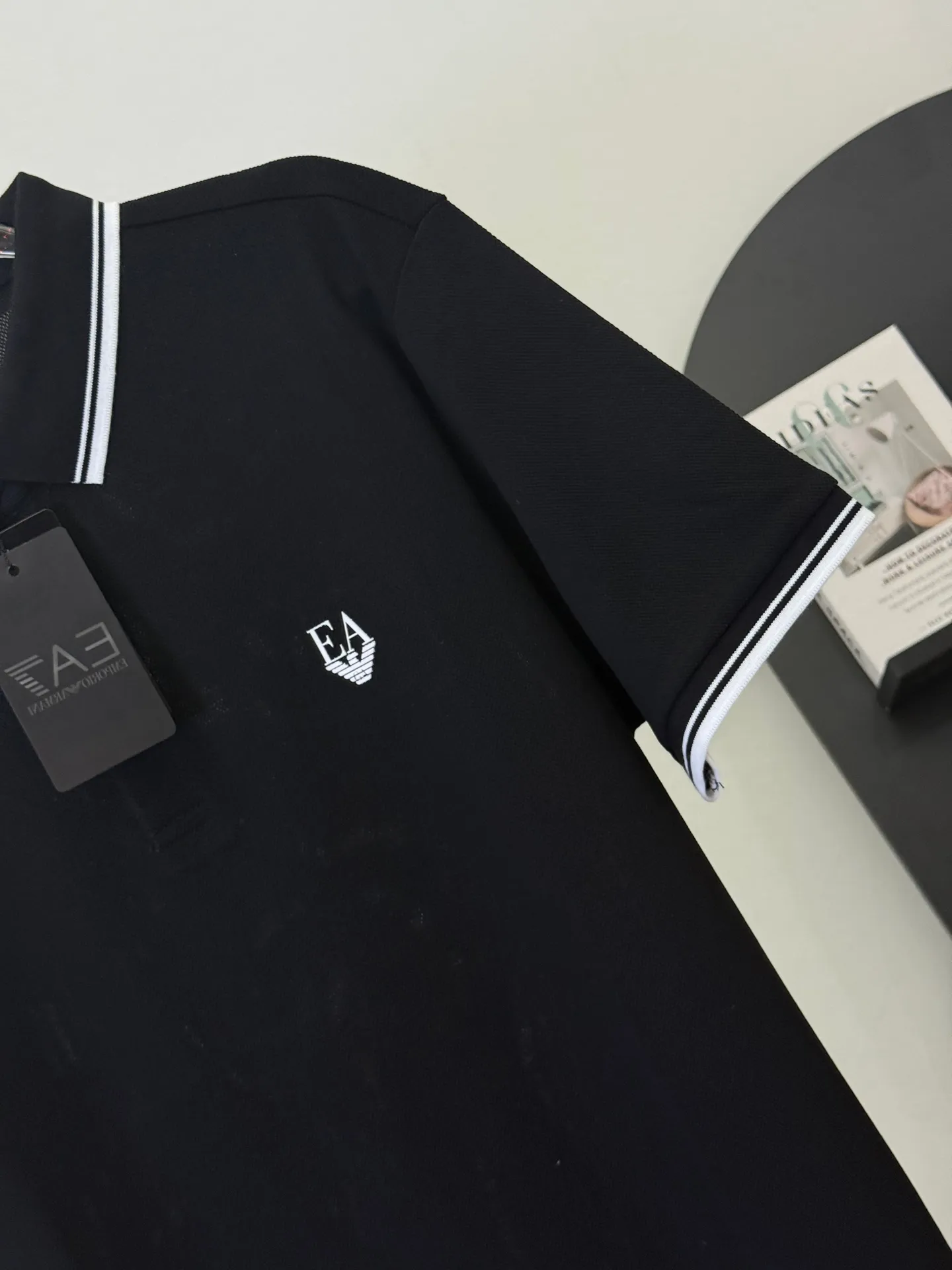 👄 EA 7 Black Bottom Slim Label Contrast Collar Polo Shirt Put Armani’s sports and leisure aesthetics into this neat black Polo. The exquisite EA embroidery logo on the chest, combined with contrasting stripe details on the collar and cuffs, is low-key yet energetic on a calm black background. It is a textured choice that can be used for daily commuting and leisure sports. We select high-count Breathable piqué cotton, which is draped and wrinkle-resistant. The upper body is refreshing and not sweaty. It fits a slightly loose version and is not flattering on your figure. It can easily create a neat, stylish and mature look. M-3XL